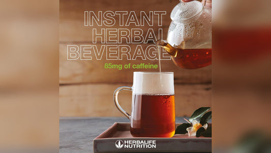 Herbal beverage with caffeine in a glass cup, pouring from a teapot on a wooden surface