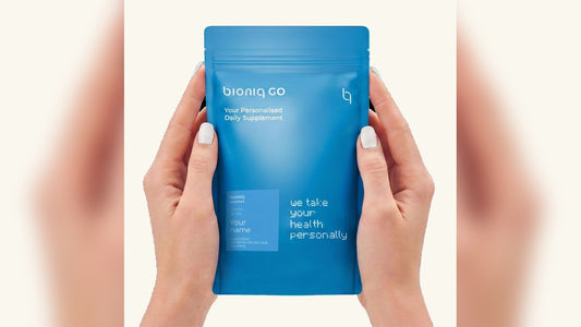 Bioniq GO personalised daily supplement pouch with the customer's name on the label, held in two hands